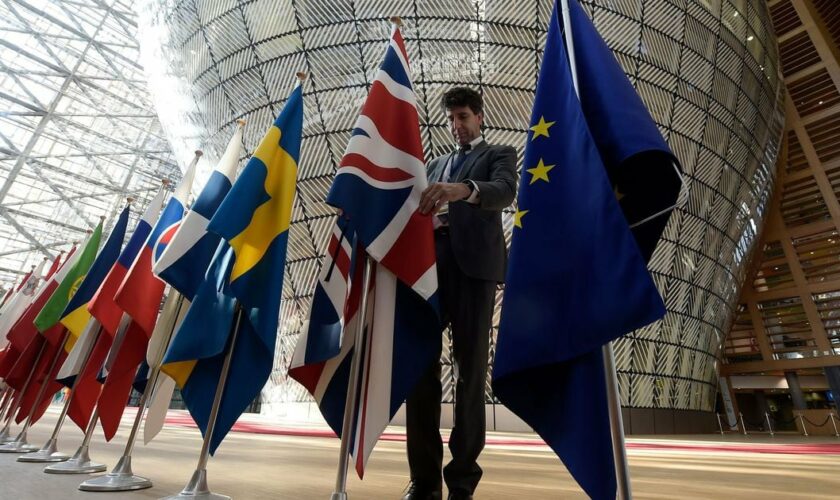 Un homme réajuste le drapeau britannique aux côtés de ceux de l'UE à Bruxelles, le 29 avril 2017