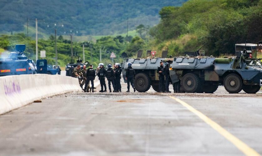 Des gendarmes mobiles sécurisent la zone pendant une opération de nettoyage de la route menant à l'aéroport de Nouméa dans le quartier de Païta, en Nouvelle-Calédonie, le 19 mai 2024