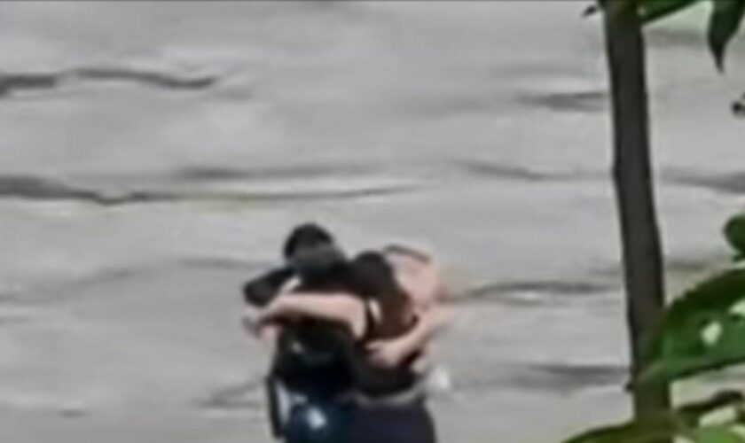 Friends seen in 'final embrace' before being swept away by flood