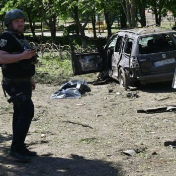 Un policier ukrainien près d'une voiture détruite par une frappe russe à Zlotchiv, dans la région de Kharkiv, le 1er mai 2024