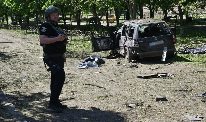 Un policier ukrainien près d'une voiture détruite par une frappe russe à Zlotchiv, dans la région de Kharkiv, le 1er mai 2024