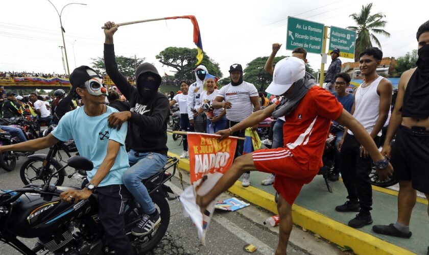 Un manifestant donne un coup de pied dans une bannière de campagne du président vénézuélien Nicolas Maduro lors d'une manifestation à Valencia (Etat de Carabobo), au Venezuela, le 29 juillet 2024