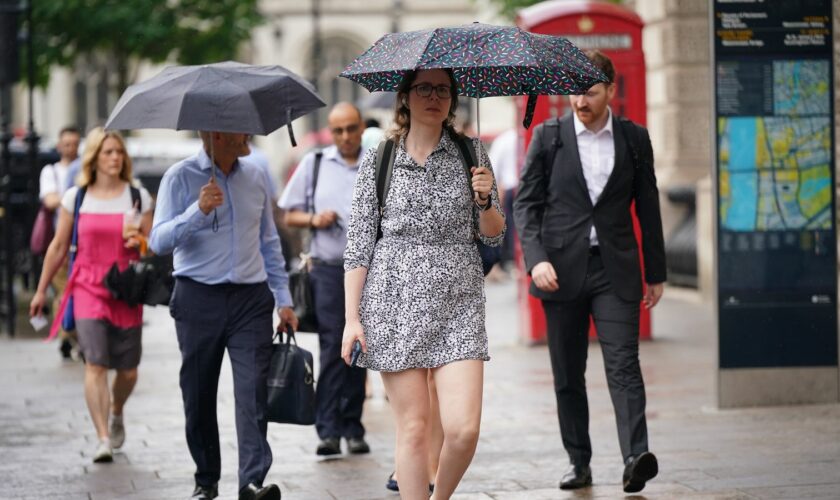 People walking in a rain shower on Whitehall in Westminster, London. Thunderstorms and hailstorms are set to sweep across parts of the UK on Thursday as temperatures reach up to 30C. Picture date: Thursday August 1, 2024.