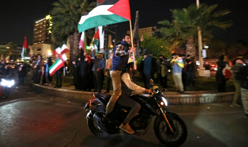 Des manifestants brandissent des drapeaux iranien et palestinien sur la place Palestine à Téhéran le 14 avril 2024, après que l'Iran a lancé une attaque de drones et de missiles contre Israël