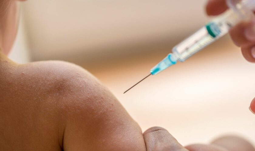 Doctor injecting a young child with a vaccination or antibiotic in a small disposable hypodermic syringe, close up of the kids arm and needle.