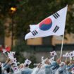 Seoyeong Kim et Sanghyeok Woo, porte-drapeaux de l'équipe de la République de Corée, sont vus en train d'agiter leur drapeau le long de la Seine lors de la cérémonie d'ouverture des Jeux Olympiques Paris 2024, le 26 juillet 2024 à Paris, France.