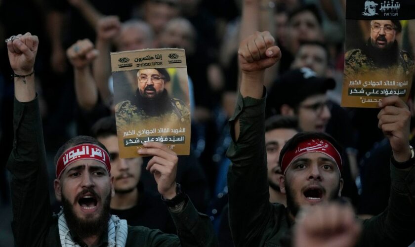 Hezbollah hold up portraits showing commander Fuad Shukr who was killed by an Israeli airstrike. Pic: AP