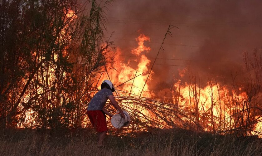 A volunteer tries to extinguish a fire in northern Athens. Pic: AP