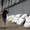 Des habitants passent devant la mairie dont les fenêtres du sous-sol sont protégées par des sacs de sable, à Koursk, le 16 août 2024 en Russie