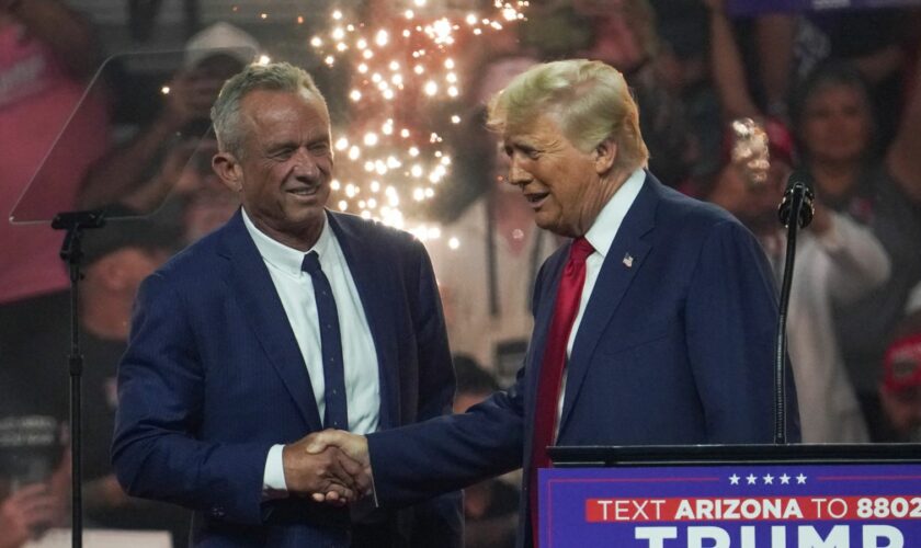 Republican presidential nominee and former U.S. President Donald Trump shakes hands with former independent presidential candidate Robert F. Kennedy Jr. during a rally in Glendale, Arizona, U.S., August 23, 2024. REUTERS/Go Nakamura