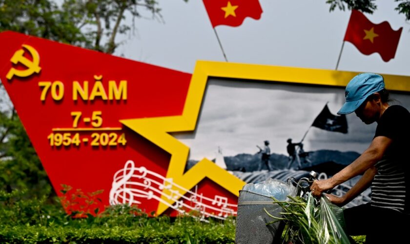 Une femme à vélo passe à Hanoï, le 25 avril 2024, devant une structure commémorant 70ème anniversaire de la victoire de Dien Bien Phu contre les troupes françaises, qui a conduit à l'émergence du Vietnam indépendant.