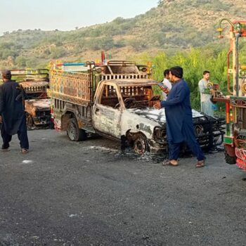 People look burnt vehicles, torched by gunmen after killing passengers, at a highway in Musakhail, a district in Baluchistan province in southwestern Pakistan, Monday, Aug. 26, 2024. (AP Photo/Rahmat Khan)