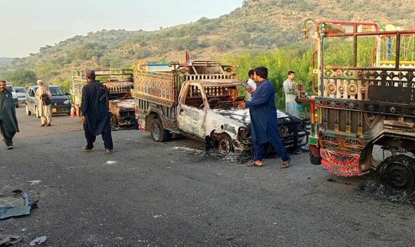 People look burnt vehicles, torched by gunmen after killing passengers, at a highway in Musakhail, a district in Baluchistan province in southwestern Pakistan, Monday, Aug. 26, 2024. (AP Photo/Rahmat Khan)