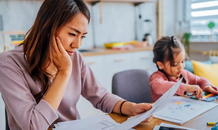 Young mother looking over finances next to daughter