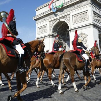 Le régiment de cavalerie de la Garde républicaine française arrive pour se préparer au défilé militaire du Jour de la Bastille sur l'avenue Foch, avec l'Arc de Triomphe en arrière-plan, à Paris, le 14 juillet 2024