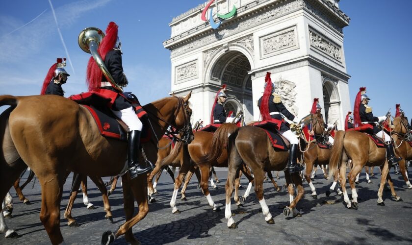 Le régiment de cavalerie de la Garde républicaine française arrive pour se préparer au défilé militaire du Jour de la Bastille sur l'avenue Foch, avec l'Arc de Triomphe en arrière-plan, à Paris, le 14 juillet 2024