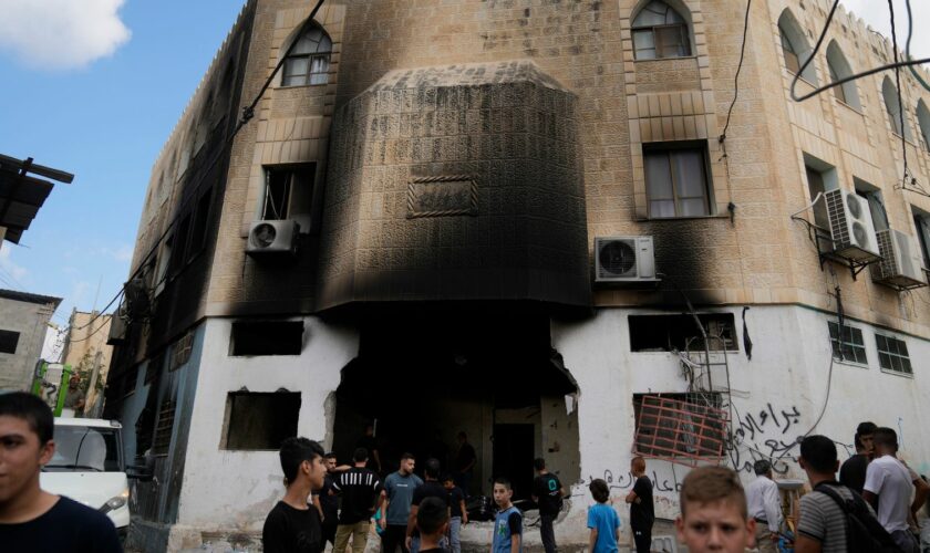 Palestinians outside a heavily damaged mosque in the West Bank. Pic: AP