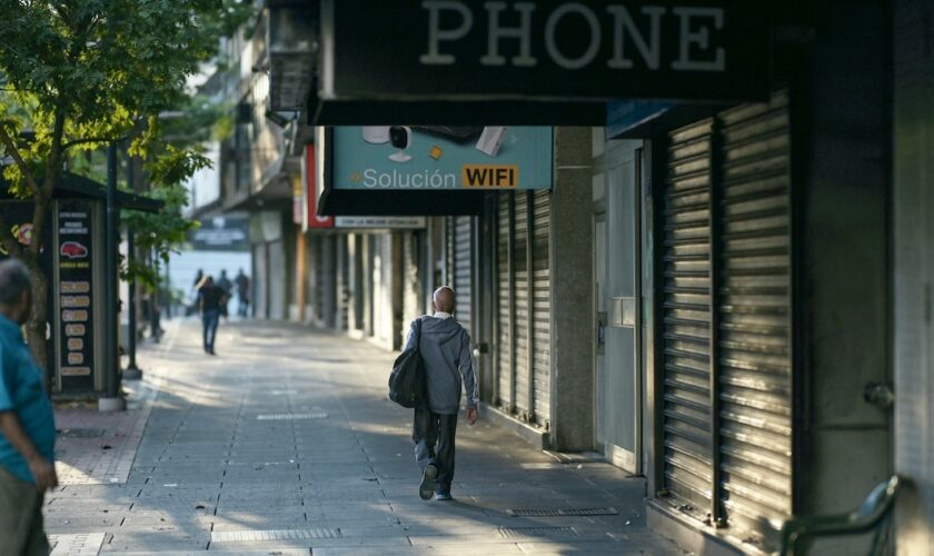 Des personnes passent devant des magasins fermés dans une rue de Caracas, au Venezuela, le 30 août 2024, à la suite d'une panne d'électricité généralisée