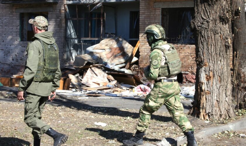 Volontaires russes en treillis, arpentent les rues de Koursk, endommagées par les frappes ukrainiennes.