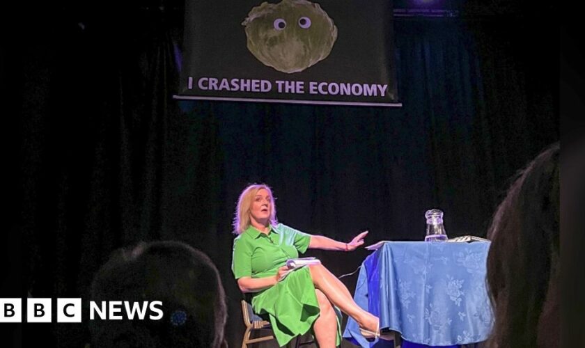 Liz Truss leaves stage as lettuce banner unfurls