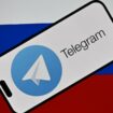 Le logo de la messagerie Telegram devant le drapeau russe.