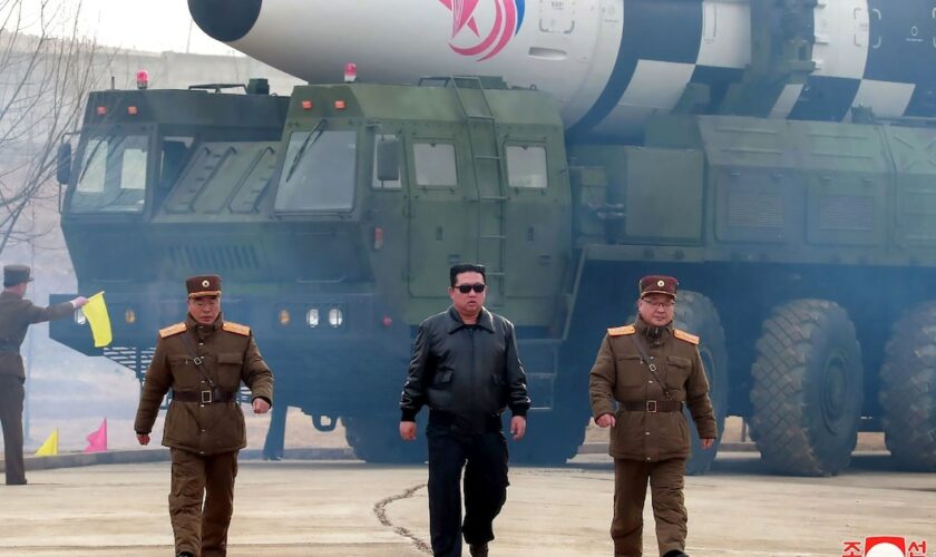 Photo diffusée le 25 mars 2022 par l'agence nord-coréenne Kcna du dirigeant nord-coréen Kim Jong Un (c) devant un missile balistique intercontinental Hwasong-17 dans un lieu non précisé en Corée du Nord, le 24 mars 2022