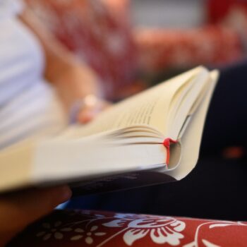 Une femme lit un livre sur un canapé.