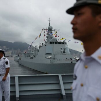 Des marins chinois à bord du Yinchuan, un destroyer de type 052D de la marine de l'Armée populaire de libération (APL), surveillent les visiteurs tandis que le destroyer de type 052C de la marine de l'APL Jinan (C, arrière-plan) est exposé au public à la base navale de Ngong Shuen Chau à Stonecutters.