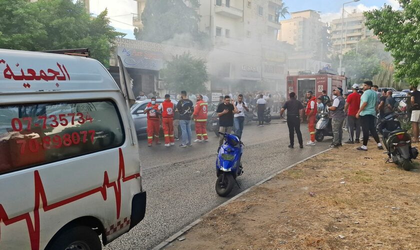 People gather as smoke rises from a mobile shop in Sidon, Lebanon September 18, 2024. REUTERS/Hassan Hankir