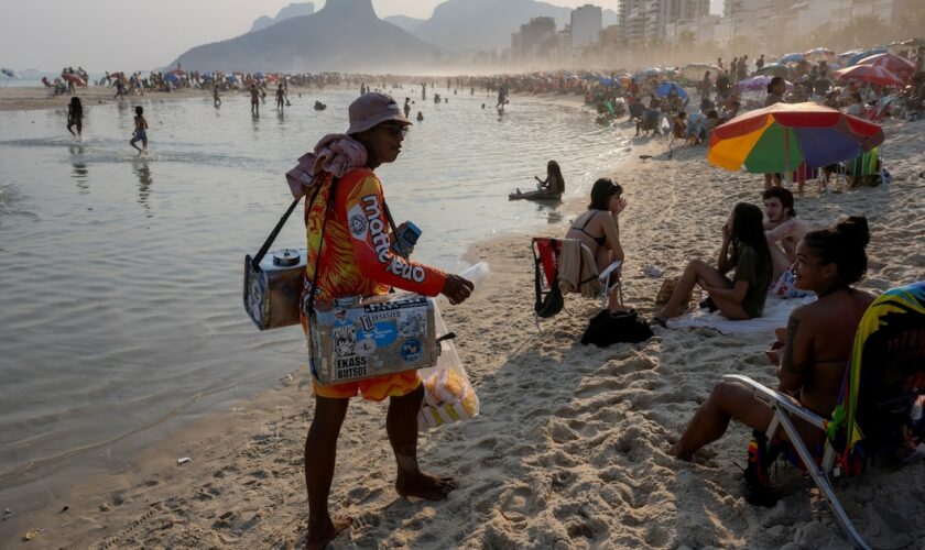 Un vendeur ambulant propose du thé au maté sur la plage d'Ipanema, à Rio de Janeiro, au Brésil, le 8 août 2024