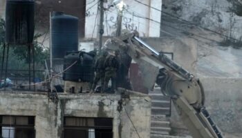 Israeli soldiers look over a rooftop where two bodies lie motionless in the West Bank town of Qabatiya. Pic: AP