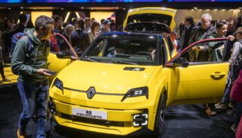 Des visiteurs à côté d'un modèle de voiture électrique Renault R5 E-Tech présenté en première mondiale par le constructeur automobile français lors de la première journée publique du Salon international de l'automobile de Genève, à Genève, le 28 février 2024. (Photo de Fabrice COFFRINI / AFP)