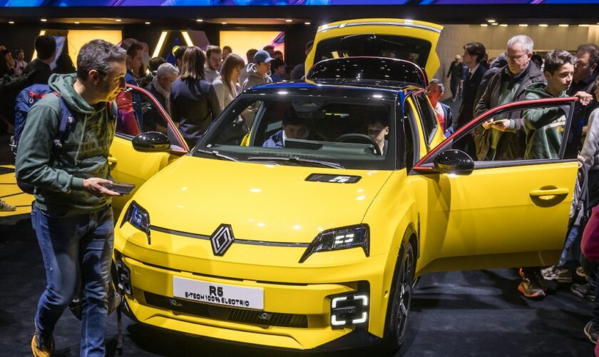 Des visiteurs à côté d'un modèle de voiture électrique Renault R5 E-Tech présenté en première mondiale par le constructeur automobile français lors de la première journée publique du Salon international de l'automobile de Genève, à Genève, le 28 février 2024. (Photo de Fabrice COFFRINI / AFP)