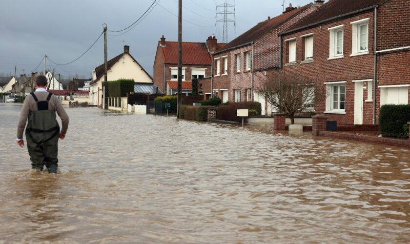 Un homme marche le 3 janvier 2024 dans une rue inondée d'Arques, dans le nord de la France, suite à la crue de l'Aa