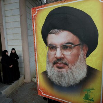 People stand near a picture of Hezbollah leader Sayyed Hassan Nasrallah during the funeral of Hezbollah member Ali Mohamed Chalbi, after hand-held radios and pagers used by Hezbollah detonated across Lebanon, in Kfar Melki, Lebanon September 19, 2024. REUTERS/Aziz Taher