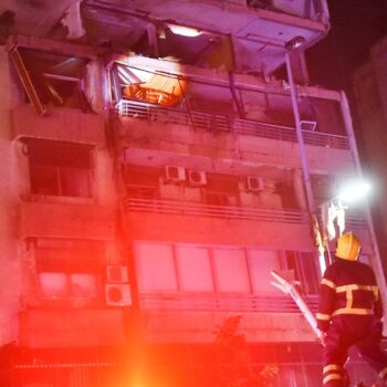 Des pompiers devant un immeuble touché par une frappe aérienne israélienne dans le quartier de Cola à Beyrouth, le 30 septembre 2024