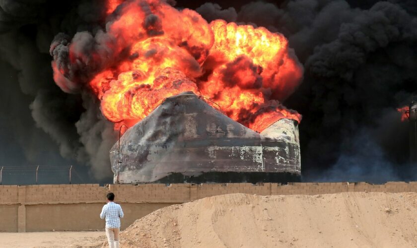 Un homme devant un incendie qui fait rage dans des réservoirs de stockage de pétrole, bombardés par Israël au port de Hodeida tenu par les rebelles Houthis au Yémen, le 21 juillet 2024