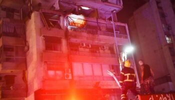 Des pompiers devant un immeuble touché par une frappe aérienne israélienne dans le quartier de Cola à Beyrouth, le 30 septembre 2024