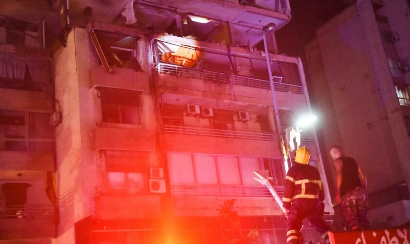 Des pompiers devant un immeuble touché par une frappe aérienne israélienne dans le quartier de Cola à Beyrouth, le 30 septembre 2024