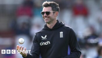 James Anderson tosses a white ball in the air while on coaching duties for England