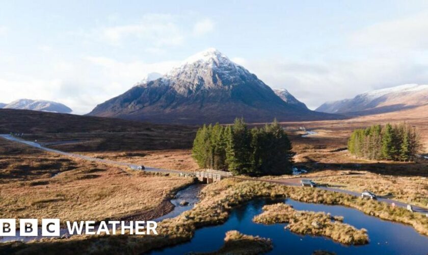 A rural road runs across the Highlands with a snow-capped mountain in the distance