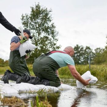 Durch einen Schutzdeich in Eisenhüttenstadt sickert Wasser. Einsatzkräfte rücken mit Sandsäcken an. Foto: Michael Ukas/dpa