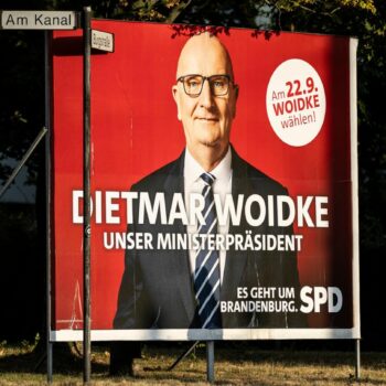 Eine Frau spaziert an einer großen Wahlplakatwand der SPD zur Brandenburg-Wahl mit Dietmar Woidke vorbei