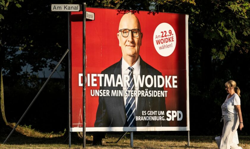 Eine Frau spaziert an einer großen Wahlplakatwand der SPD zur Brandenburg-Wahl mit Dietmar Woidke vorbei