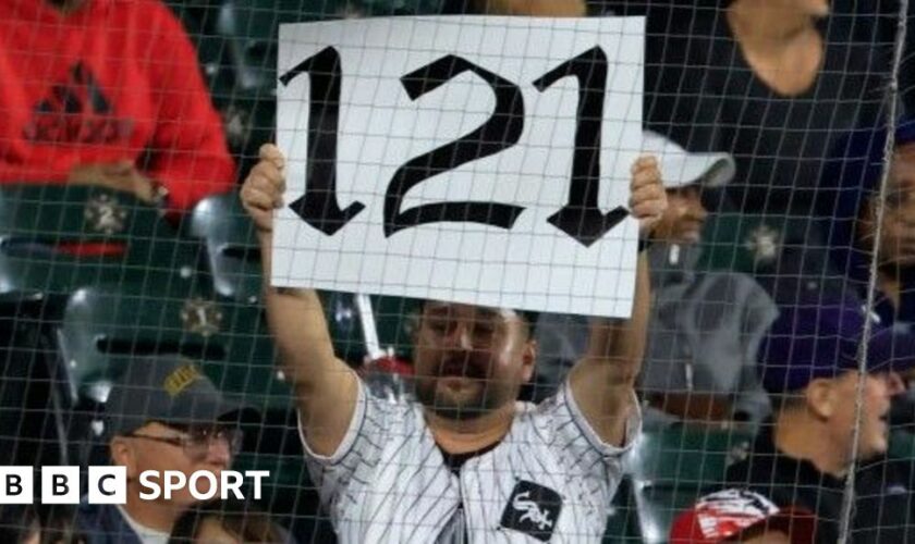 A fan holds up a '121' sign to mark the Chicago White Sox's record defeat