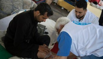 Le docteur Bertrand Chatelain de l'ONG Médecins du Monde (MdM) examine un réfugié lors d'une maraude dans le camp de migrants du quartier Stalingrad à Paris, le 12 juillet 2023. (Photo par JULIEN DE ROSA / AFP)