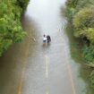 People wade along a flooded road in Offord Cluny, Cambridgeshire last week. Pic: PA