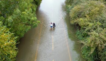 People wade along a flooded road in Offord Cluny, Cambridgeshire last week. Pic: PA