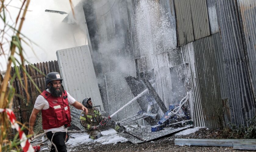 An Israeli firefighter works to put out a fire after a projectile landed at the scene in Kfar Chabad. Pic: Reuters