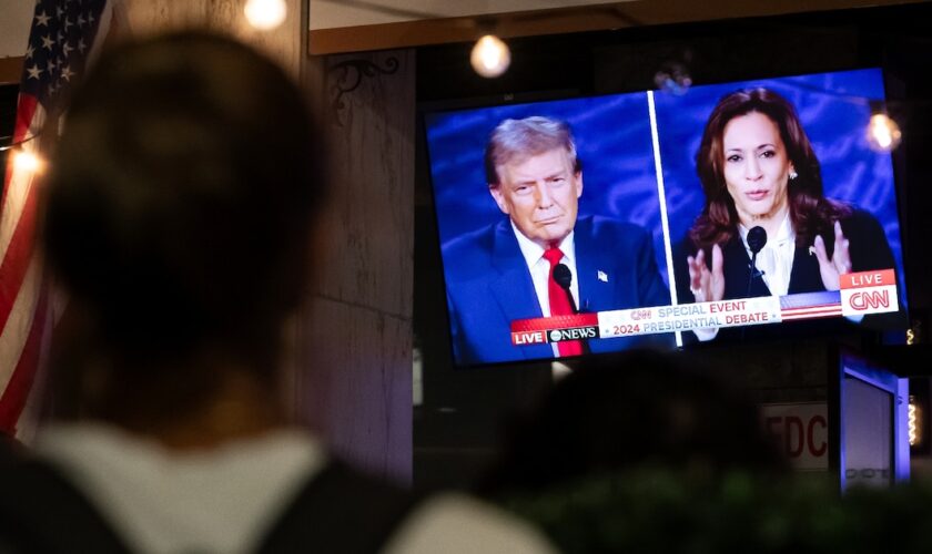 Un passant devant un bar à Washington diffusant le débat entre Donald Trump et Kamala Harris, le 10 septembre 2024